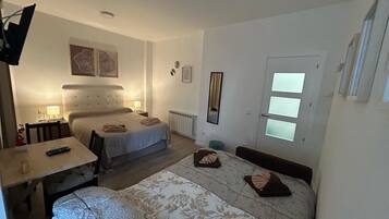 Habitación de hotel con dos camas, una mesa de comedor, una silla, un espejo y una ventana con persianas.