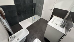 A bathroom with a glass shower enclosure, a white sink, and a bathtub. - Habitaciones en Embajadores (Madrid)