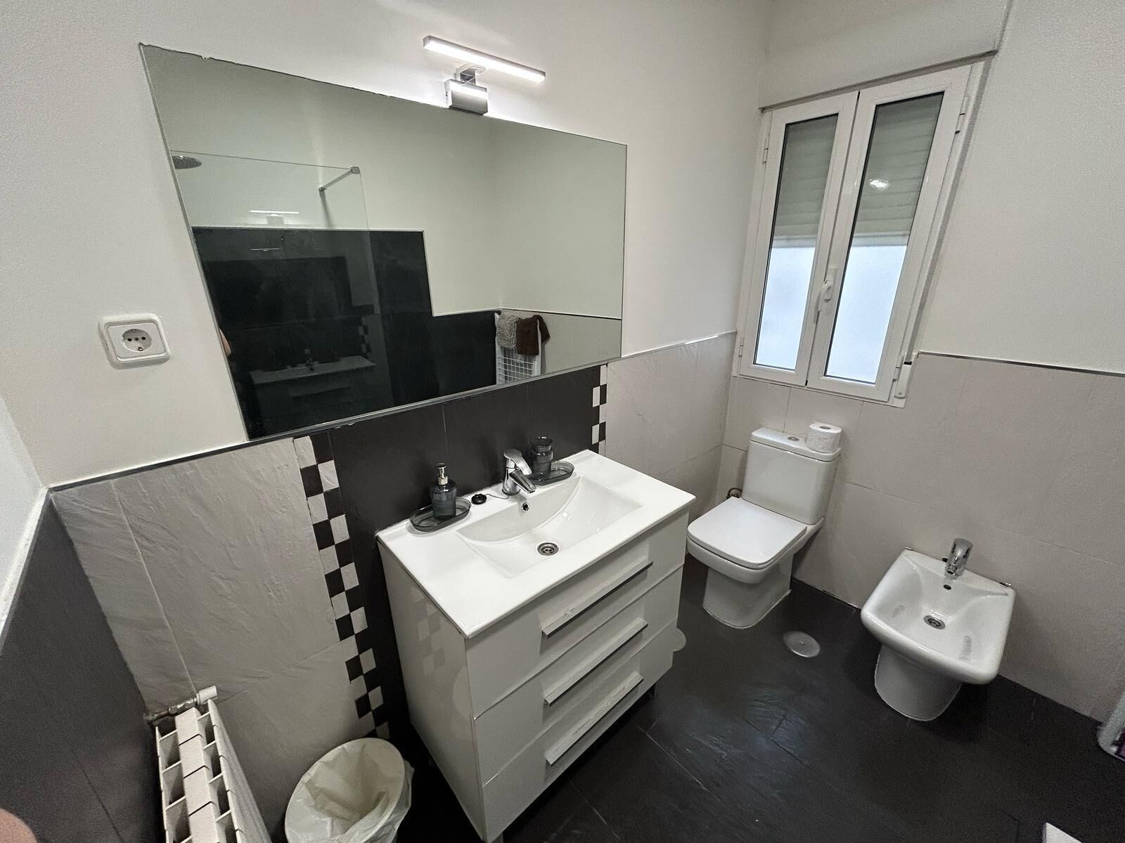 Un baño moderno con un lavamanos blanco, un espejo, un inodoro y un bidé.