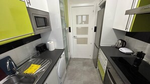 A compact kitchen with a microwave, toaster, sink, and a coffee maker. - Habitaciones en Embajadores (Madrid)