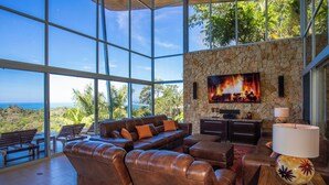 A spacious living area with leather sofas, a stone fireplace, and a large TV. - Casa Pura Vista - Best View Home in Manuel Antonio (Manuel Antonio)