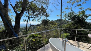A bathroom with a freestanding bathtub, a metal railing, and a view of a forested landscape. - Casa Pura Vista - Best View Home in Manuel Antonio (Manuel Antonio)