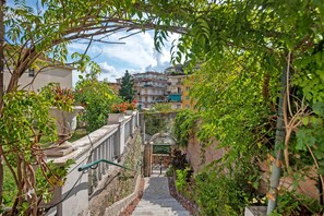 A staircase leading to a gated entrance surrounded by greenery and buildings.