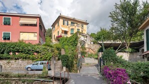 Une rue étroite, bordée de bâtiments des deux côtés, avec une voiture garée à gauche et un pont de pierre au centre.