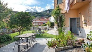 Une terrasse avec une table et des chaises, un petit jardin et un bâtiment doté d’une porte et d’une fenêtre.