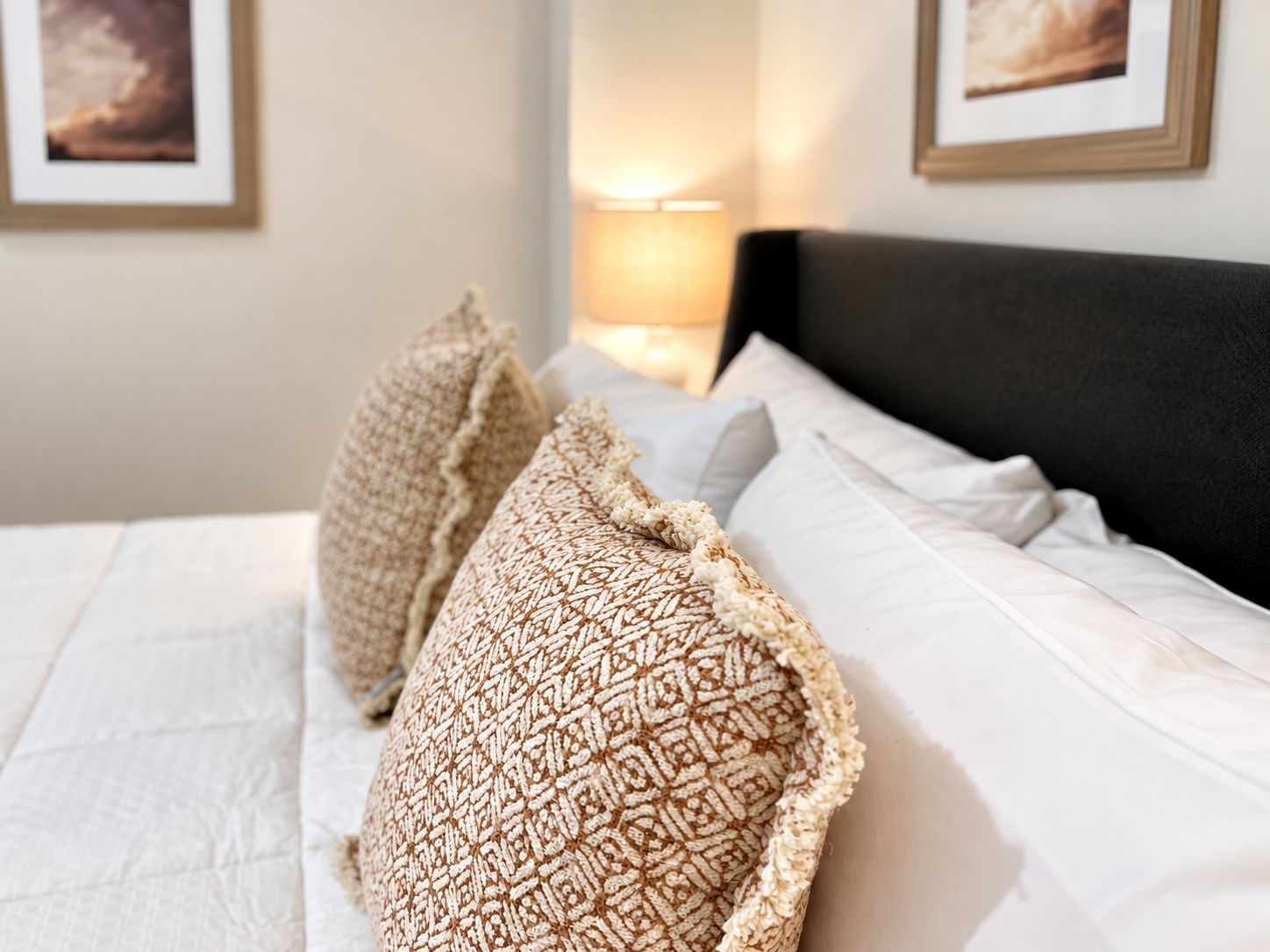 A neatly made bed with patterned pillows and a white comforter.