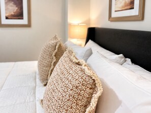 A neatly made bed with patterned pillows and a white comforter.