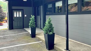 A building with a covered entrance, potted plants, and a parking lot.