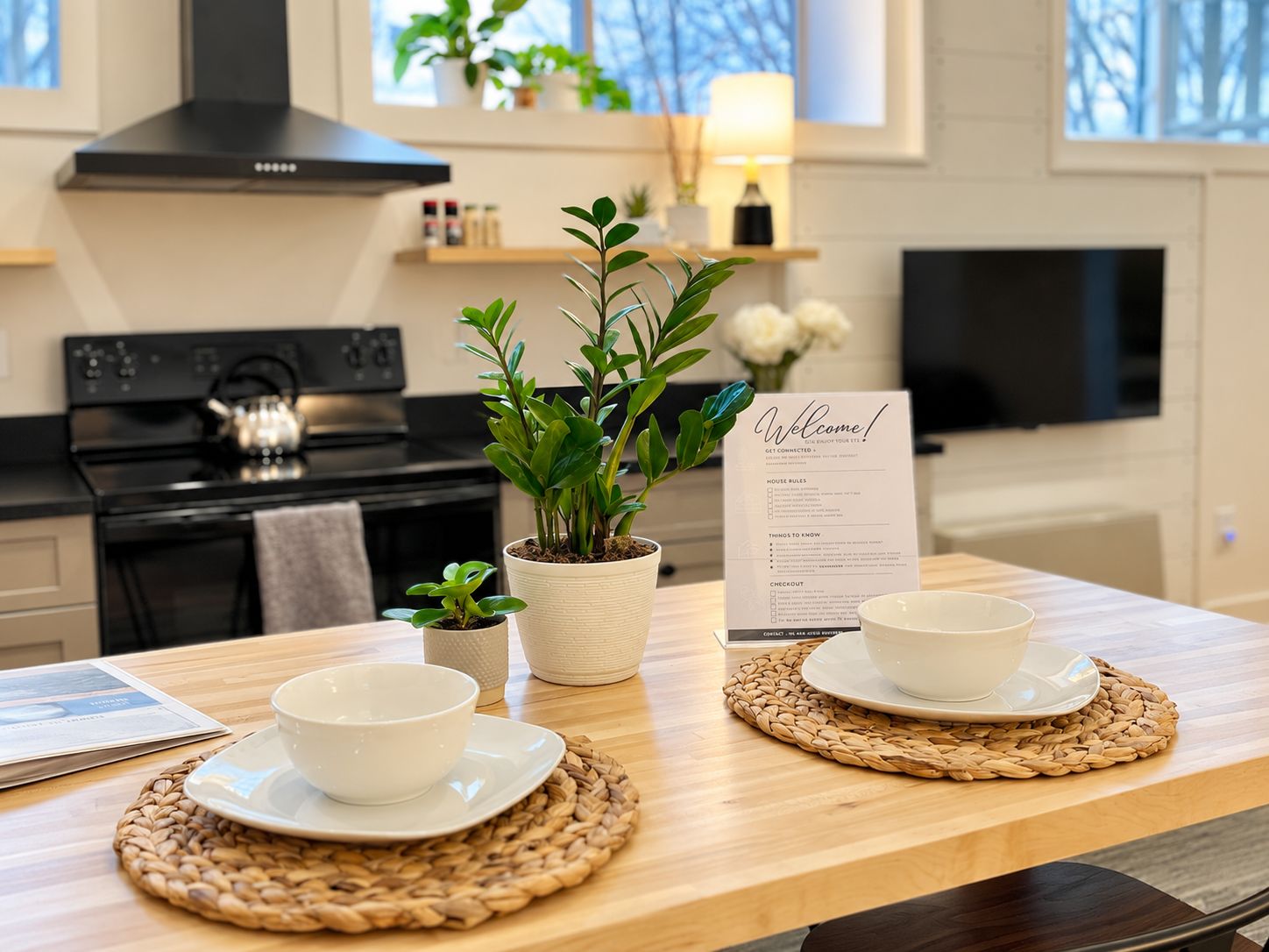 Une cuisine équipée d’une cuisinière, agrémentée d’une plante en pot et d’une pancarte de bienvenue.