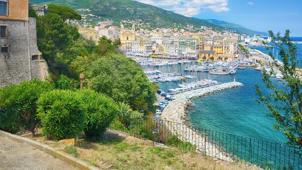 A coastal town with a marina, historic buildings, and a stone wall.