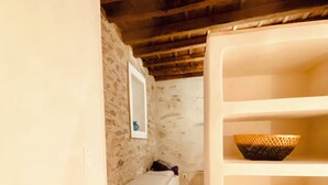 A room with a stone wall, a white sink, a white shelf, and a hexagonal tiled floor.