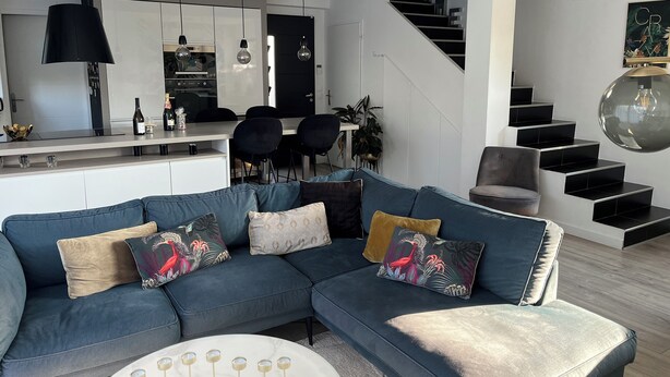 A modern living room with a sectional sofa, a dining area with a kitchen in the background, and a staircase leading to an upper level. - Beautiful contemporary house for 8 people (Lattes)