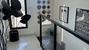 A modern interior with a staircase, a wall of decorative plates, and a potted plant. - Beautiful contemporary house for 8 people (Lattes)