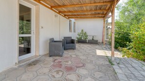 Un patio techado con suelo de piedra hexagonal, muebles de mimbre y plantas en macetas.