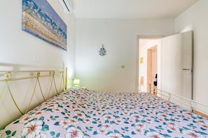 Ein Schlafzimmer mit floralem Bettbezug, einer Wanduhr und einem Gemälde.