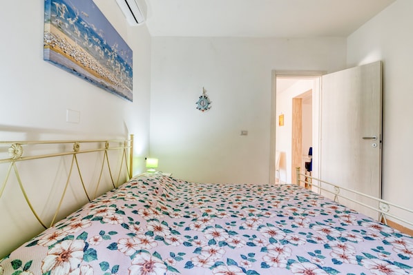 Een slaapkamer met een bloemenbedekker, een wandklok en een schilderij.