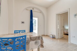 Zona pranzo con tavolo e sedie, una tenda blu e una vista attraverso un arco.