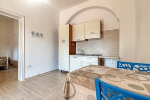 A compact kitchen with white cabinets, a built-in stove, and a dining area with a table and chairs.