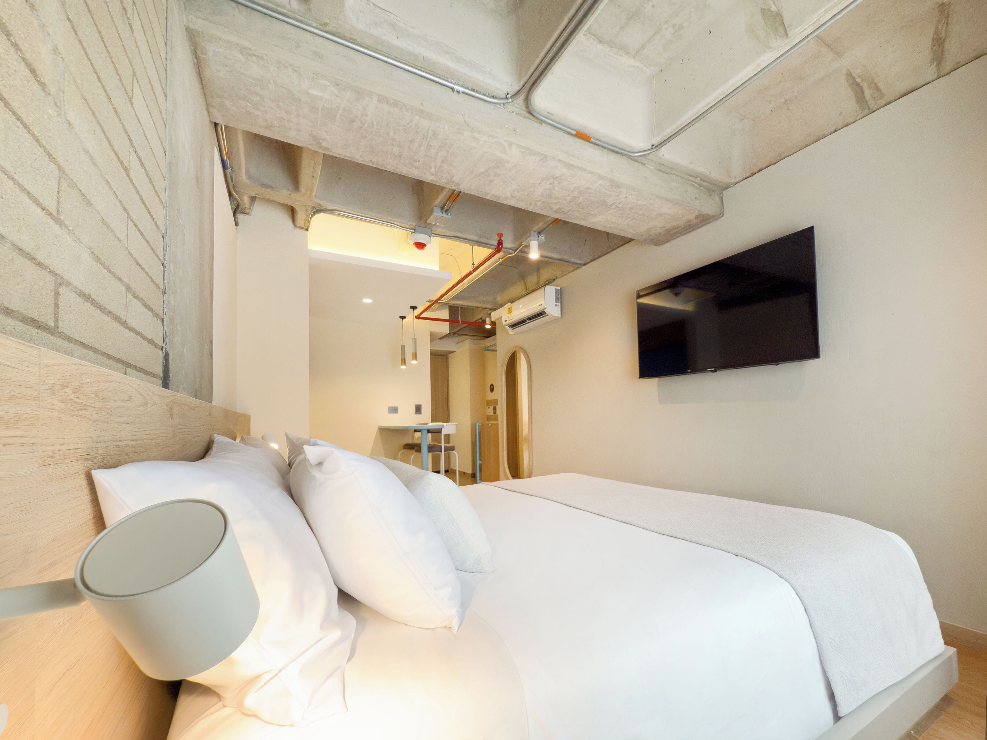 Una camera d'albergo moderna con un letto grande, una TV a schermo piatto montata a parete e un condizionatore d'aria.