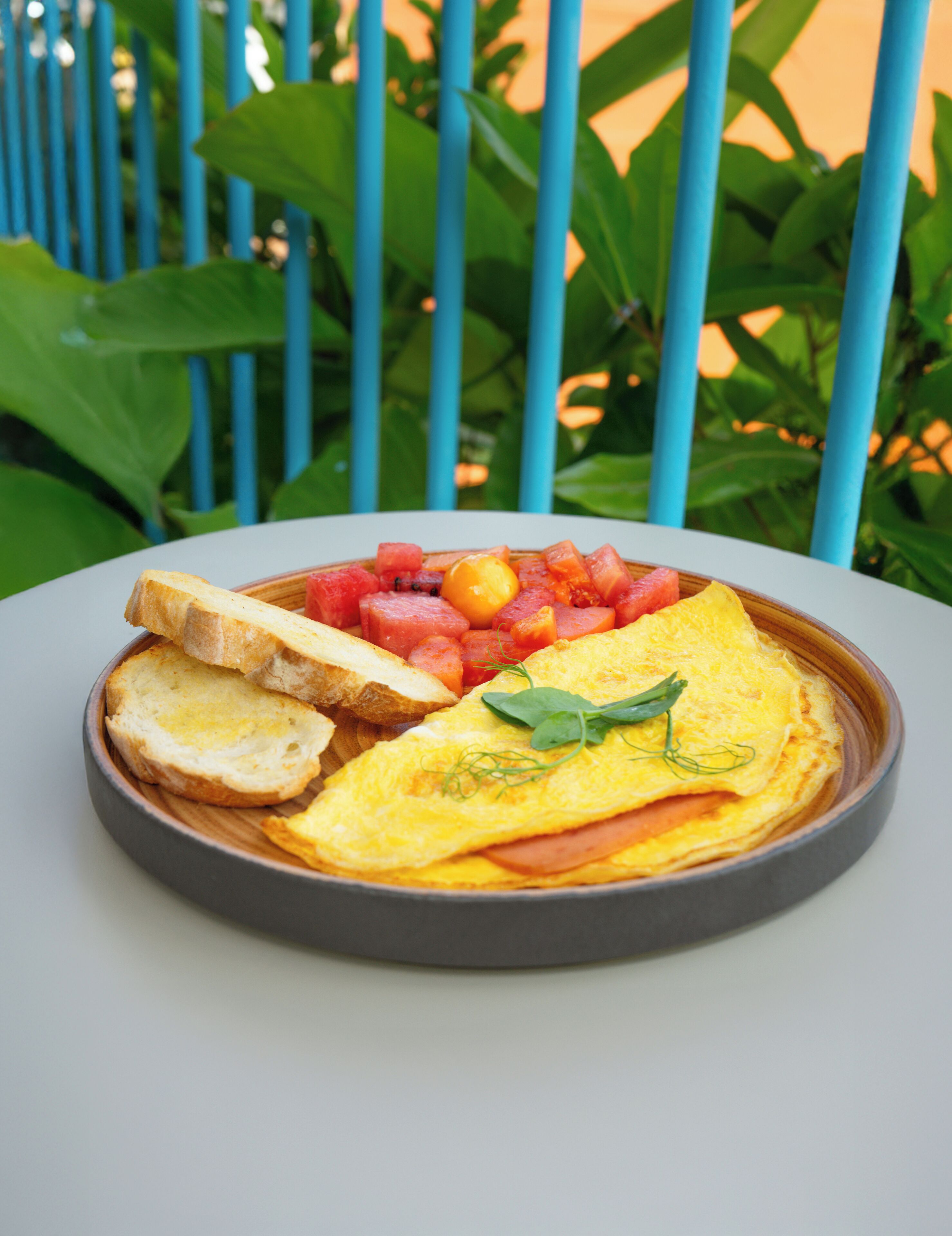 Un plato de comida con tostadas, huevos y fruta sobre una mesa.