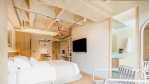 A modern hotel room with a bed, a TV, a small desk, and a bathroom with a shower and toilet. - Hotel Once22 (Sabaneta)