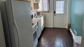 Cocina peque ña con refrigerador, lavamanos y alacenas.