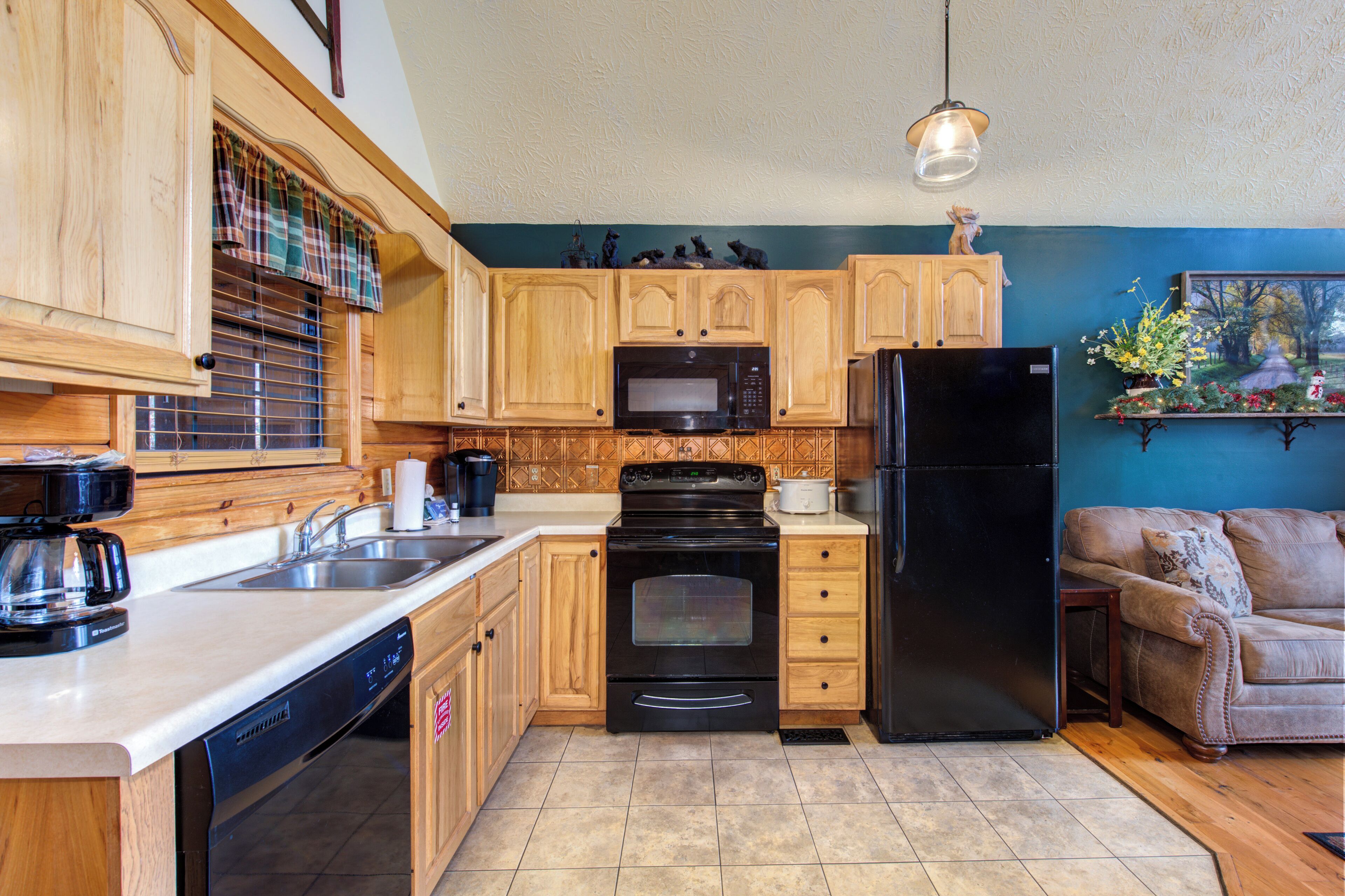 A kitchen with wooden cabinets, a black refrigerator, a microwave, and a dishwasher.