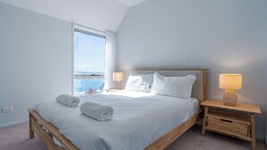 Una camera da letto con un letto in legno, due lampade sui comodini, una finestra con vista e un comodino con un cassetto.
