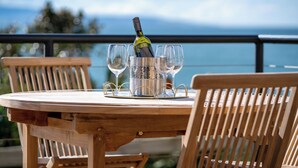 Un tavolo in legno con una bottiglia di vino e bicchieri, con vista su un panorama suggestivo.