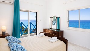 A bedroom with a bed, a dresser, a mirror, a nightstand, and a view of the ocean. - Panorama Villa - Four Bedroom Villa, Sleeps 8 (Pomos)