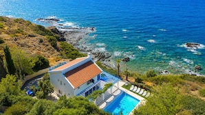 A coastal property with a swimming pool, a terrace with lounge chairs, and a view of the sea. - Panorama Villa - Four Bedroom Villa, Sleeps 8 (Pomos)