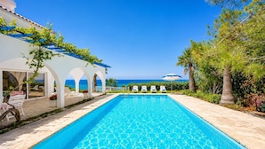 A swimming pool with lounge chairs, a covered seating area, and a view of the sea. - Panorama Villa - Four Bedroom Villa, Sleeps 8 (Pomos)