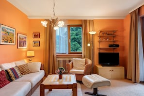 Een gezellige woonkamer met een bank, fauteuil, salontafel en tv-meubel.