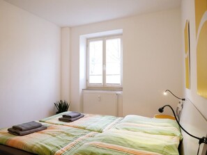 Un dormitorio con cama, ventana, radiador y una planta.