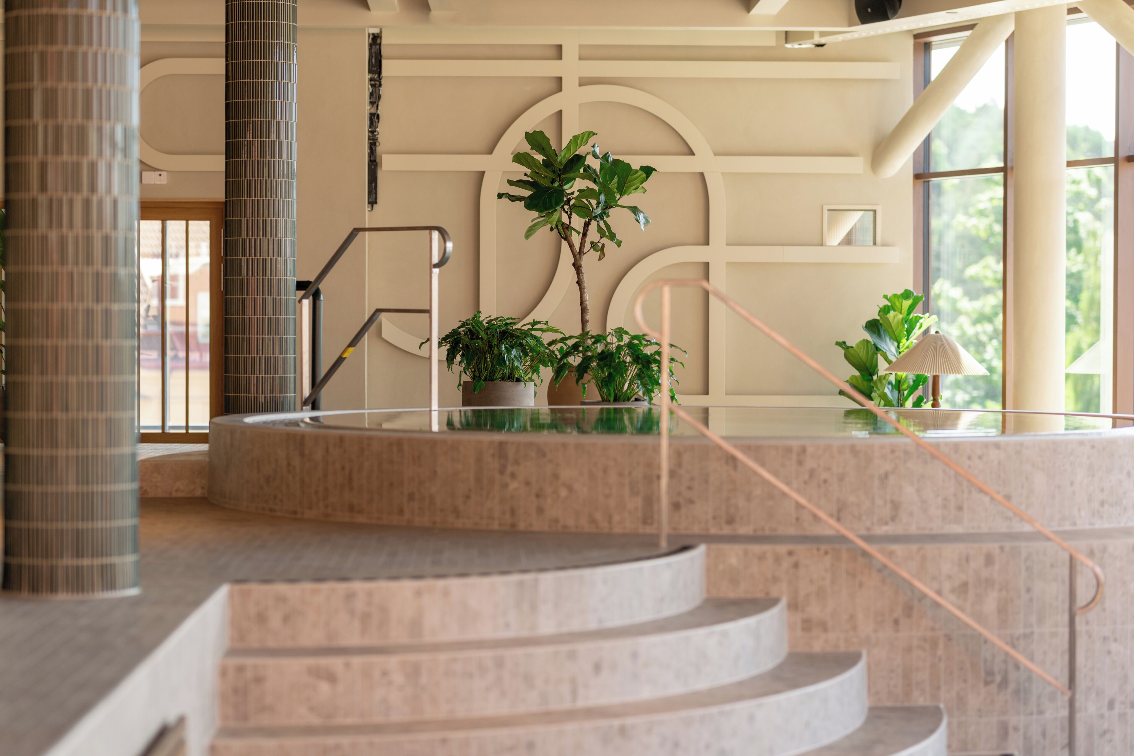 A modern interior with a spiral staircase, large windows, and potted plants.