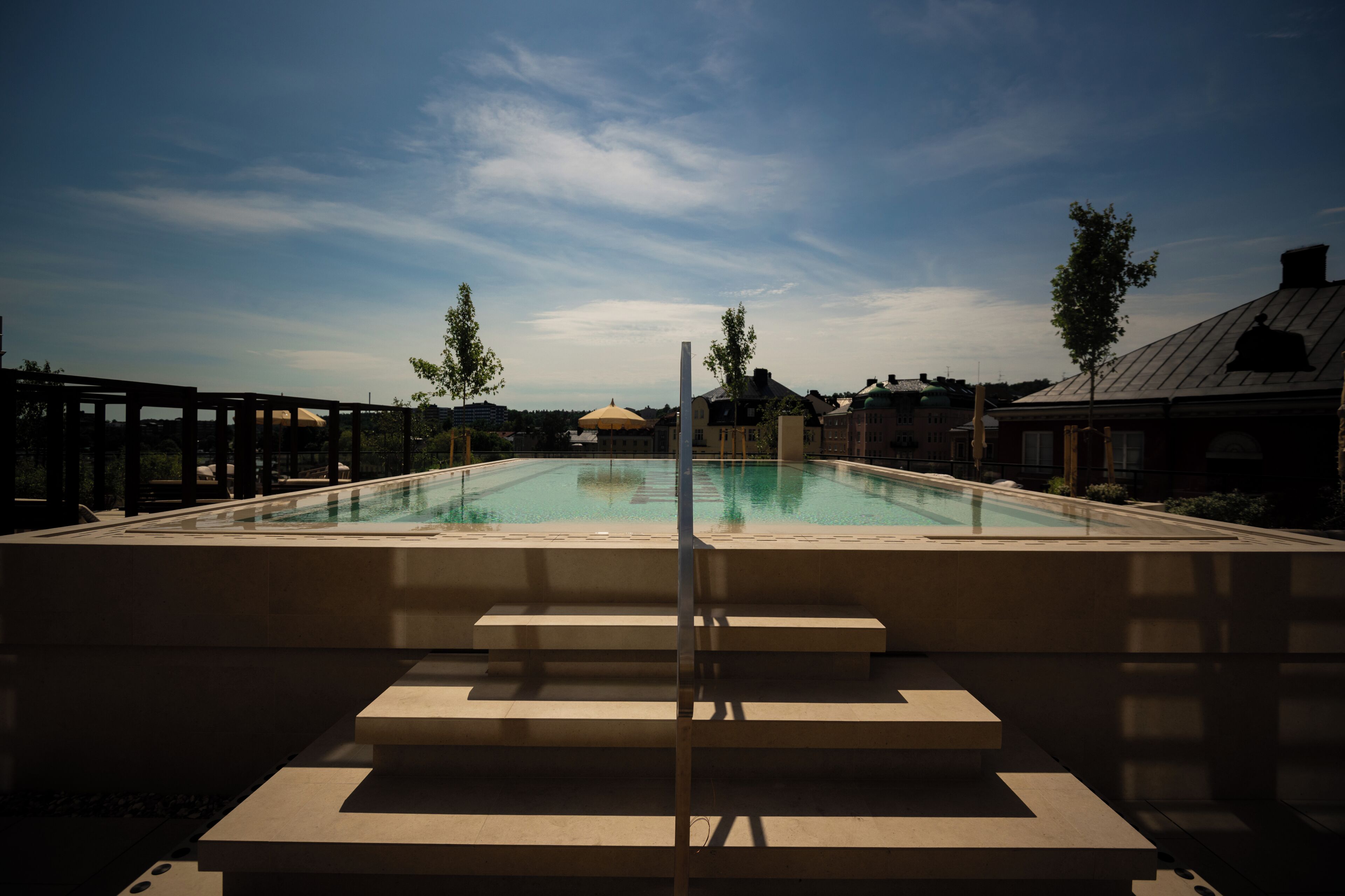 A swimming pool with steps leading up to it, surrounded by a wooden deck and a clear sky.