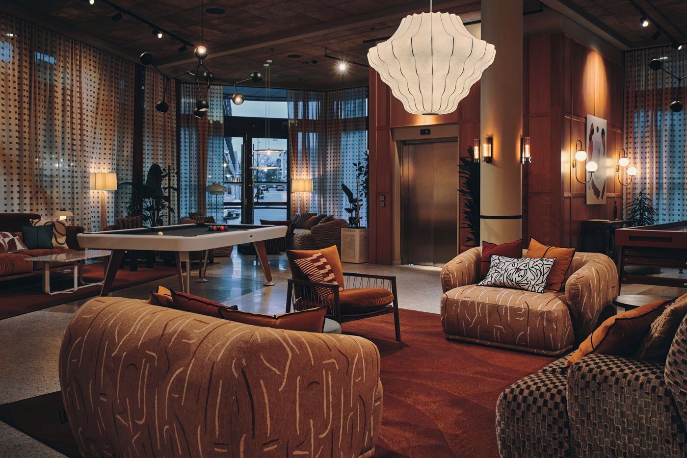 A spacious lobby with a pool table, comfortable seating, and a large chandelier.
