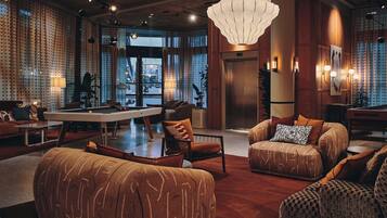 A spacious lobby with a pool table, comfortable seating, and a large chandelier.