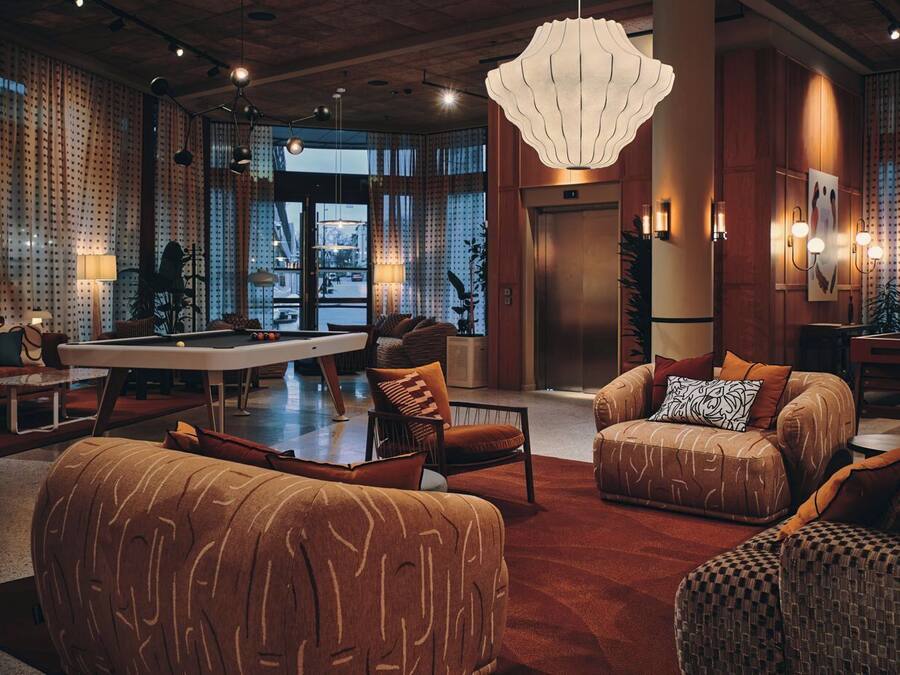 A spacious lobby with a pool table, comfortable seating, and a large chandelier.