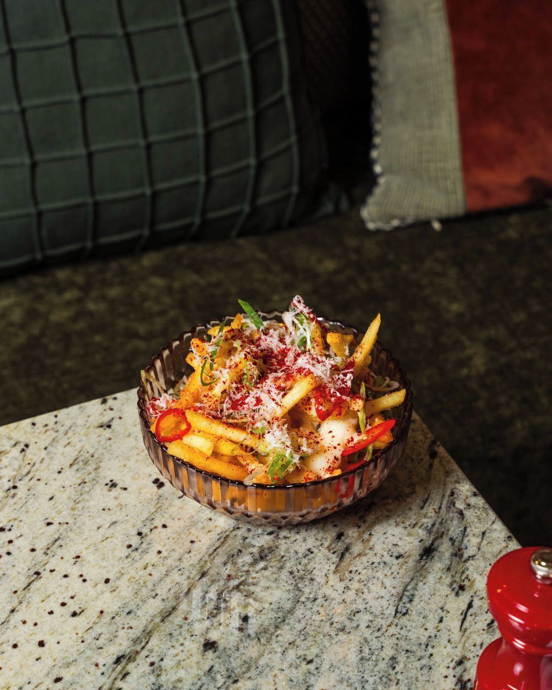 A bowl of food on a marble surface with a green cushion in the background.