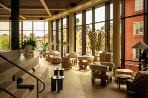 A spacious lobby with a staircase, comfortable seating, and large windows offering a view of the city. - The Dock (Södertälje)