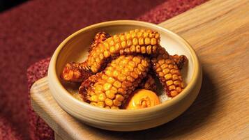 A bowl of grilled corn on the cob on a wooden table.