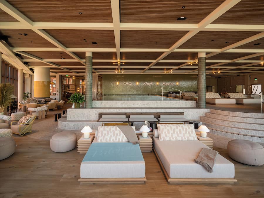 A spacious lobby with a pool area, multiple seating arrangements, and a staircase leading to upper levels.