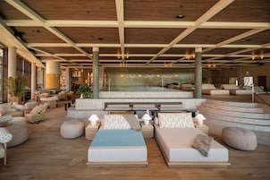 Amplio vestíbulo con zona de piscina, diversas opciones de asientos y una escalera que conduce a niveles superiores.