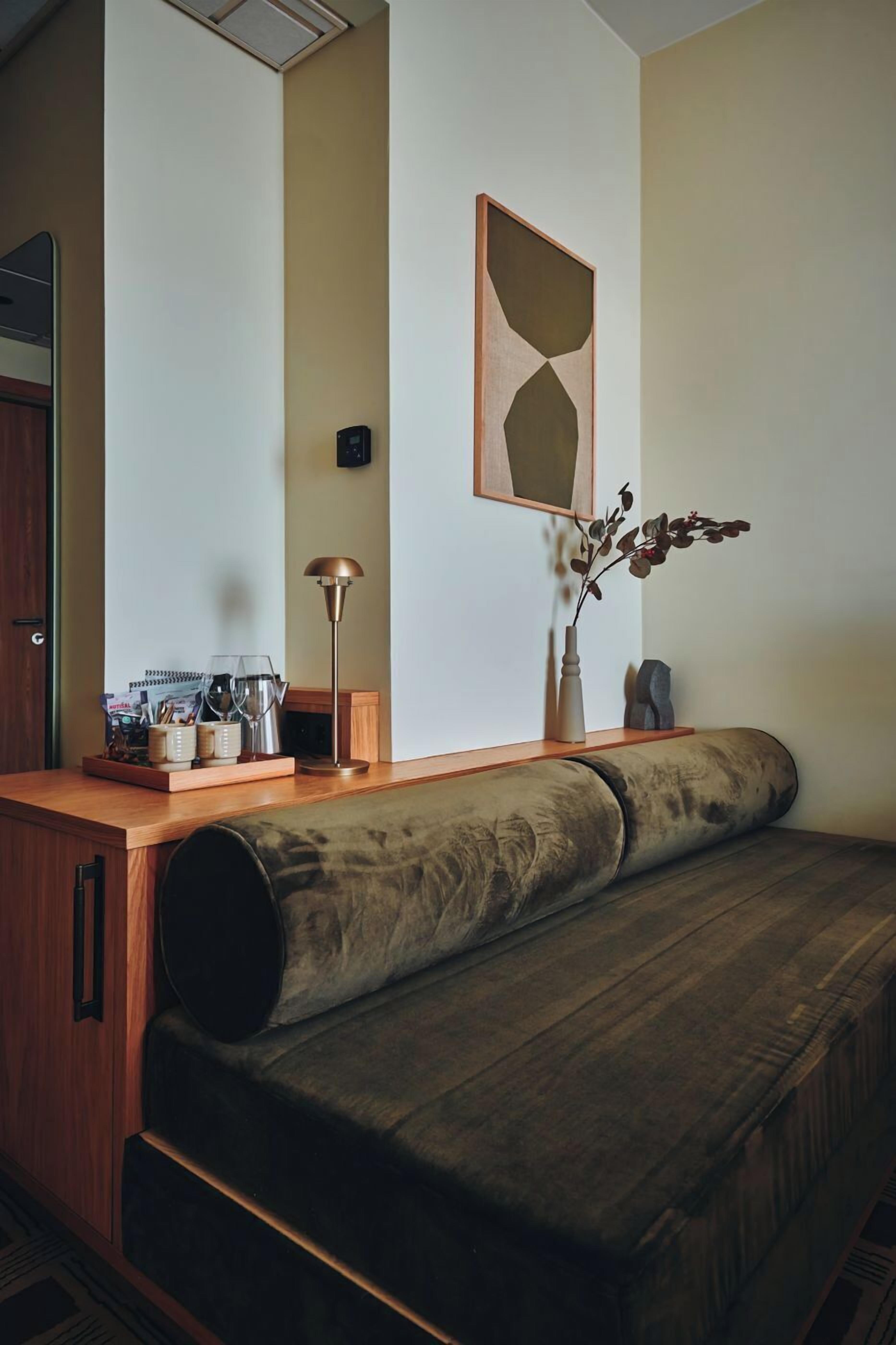 Una habitación acogedora con un banco de madera, una estación de café y una obra de arte abstracto en la pared.