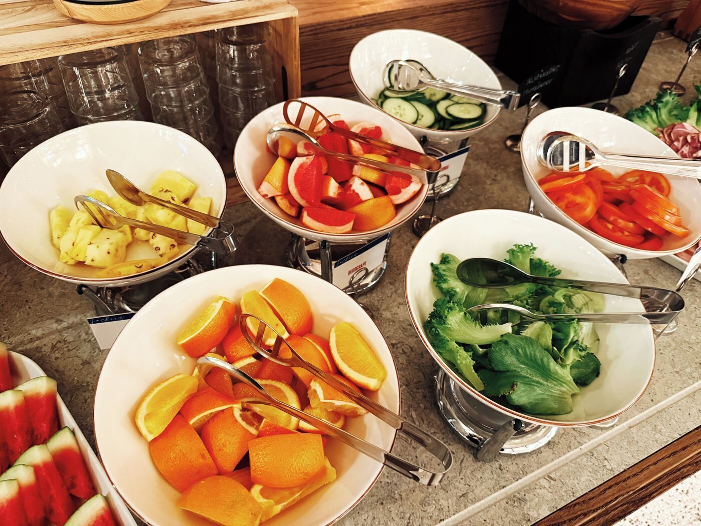 Un bufé con diversas frutas y verduras, incluyendo naranjas, sandía y brócoli.