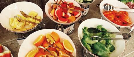 Un bufé con diversas frutas y verduras, incluyendo naranjas, sandía y brócoli.