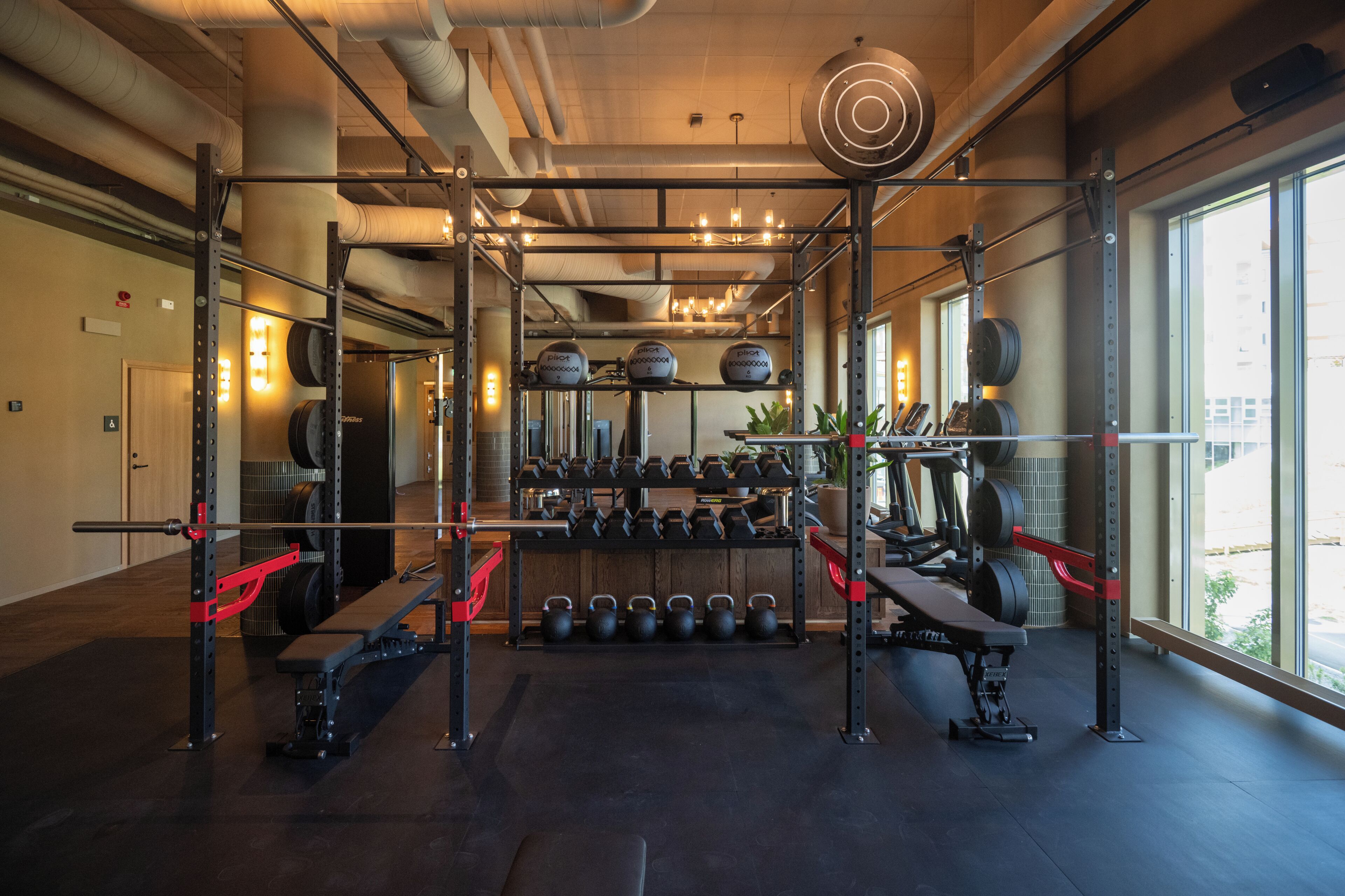 Un gimnasio con equipo de levantamiento de pesas, una banca y pesas de mancuerna.