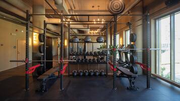 Un gimnasio con equipo de levantamiento de pesas, una banca y pesas de mancuerna.