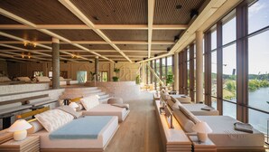 A modern hotel lobby with a long reception desk, multiple seating areas, and large windows offering a view of a body of water. - The Dock (Södertälje)
